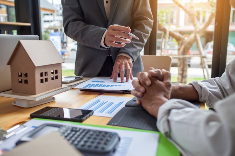 real estate agent at desk speaking with clients
